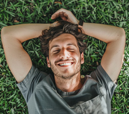closeup of man laying on the grass with his hands behind his head